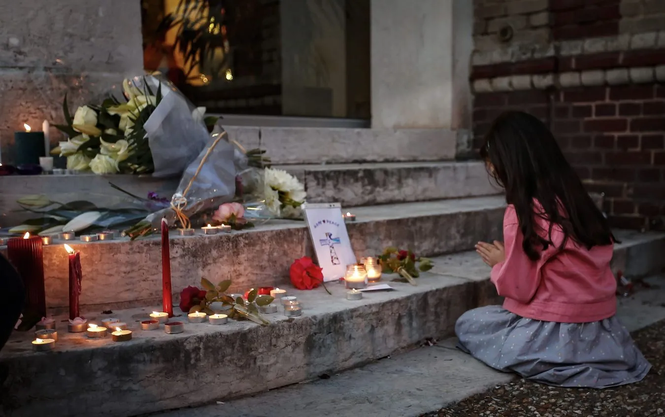 Dziewczynka modli się przed wejściem do kościoła w Saint-Etienne-du-Rouvray