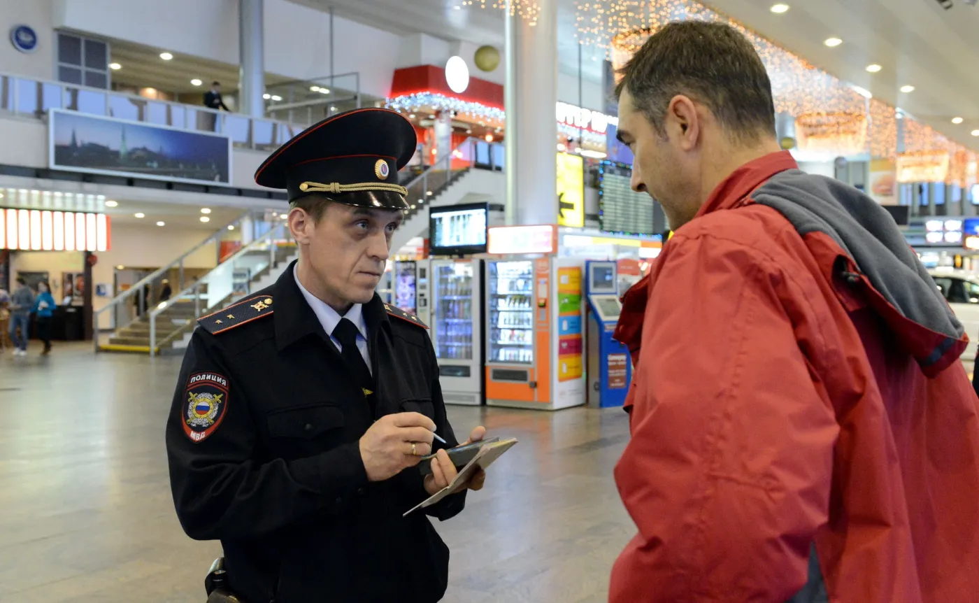 Rosyjski policjant kontroluje mężczyznę na moskiewskim lotnisku