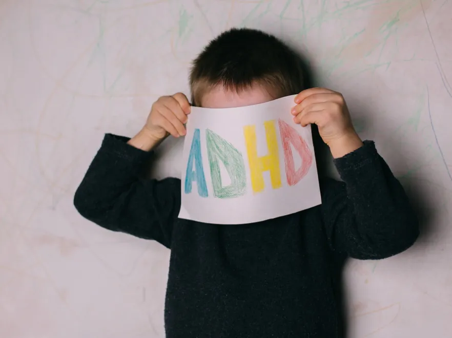 Dziecko z trzyma kartkę z napisem ADHD.