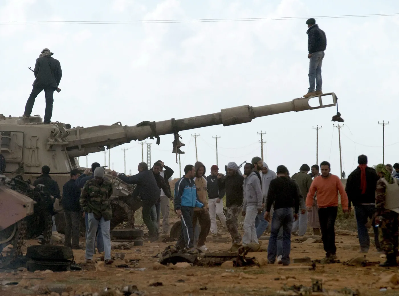 Rebelianci na spalonym czołgu, należącym do sił Muammara Kadafiego, zniszczonym podczas francuskiego nalotu 25 km od Bengazi
