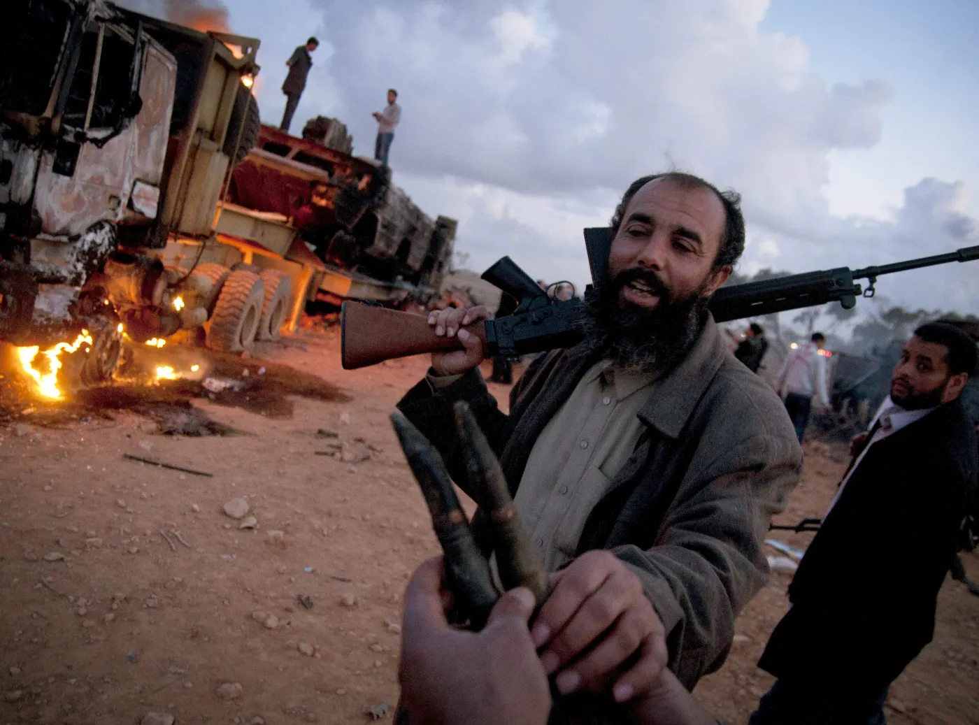 Rebeliant przed spalonym pojazdem wojskowym, należącym do sił Muammara Kadafiego, zniszczonym podczas francuskiego nalotu 25 km od Bengazi