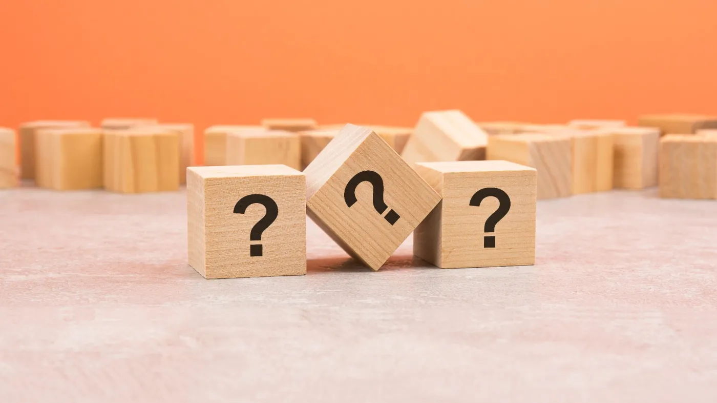 Three,Question,Marks,On,Wooden,Blocks,On,Light,Orange,Background.
