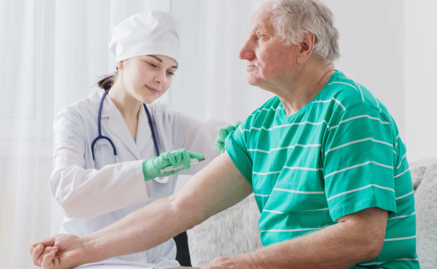 Szczepienie. Pielęgniarka szczepi starszego mężczyznę