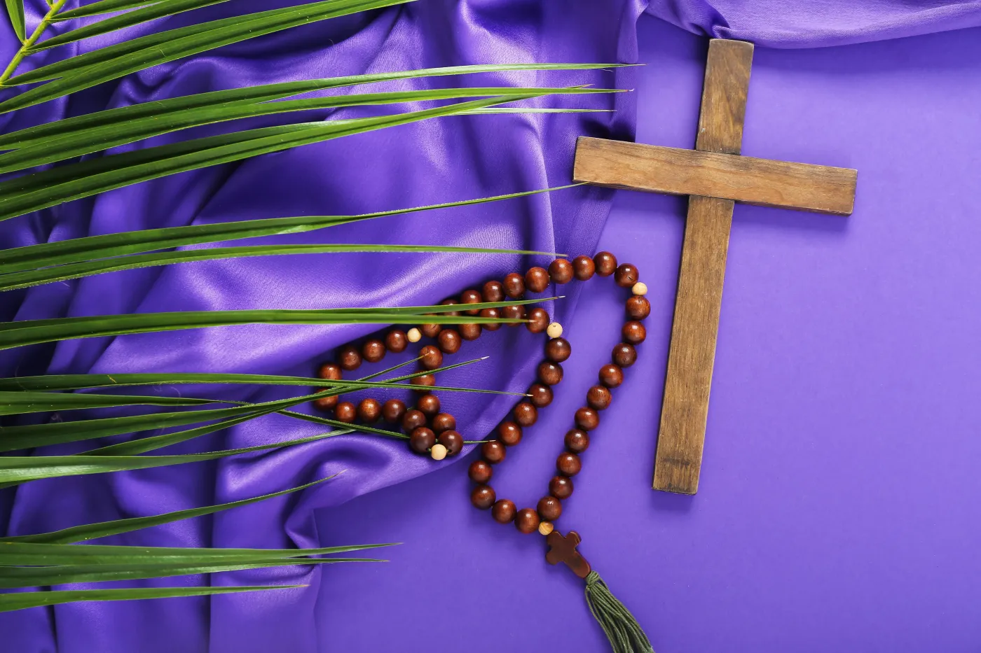 Wooden,Cross,With,Prayer,Beads,,Palm,Leaf,And,Purple,Fabric