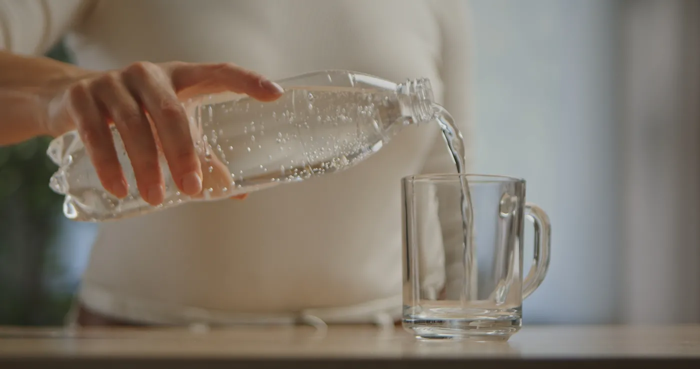 A,Woman,Hand,Pouring,Clear,Sparkling,Water,From,A,Plastic