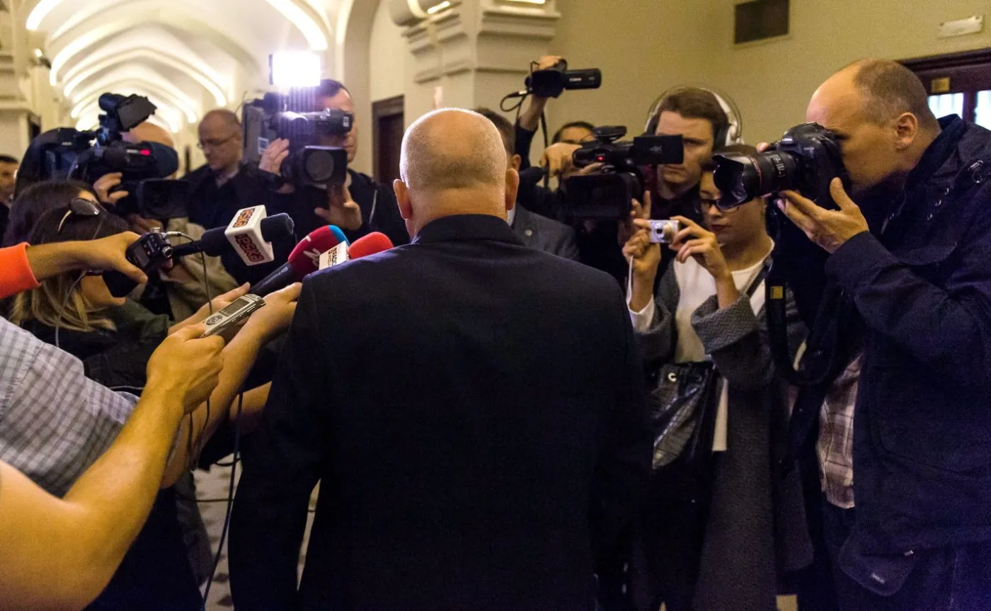 Oskarżony Piotr R. (tyłem) rozmawia z dziennikarzami na korytarzu sądowym