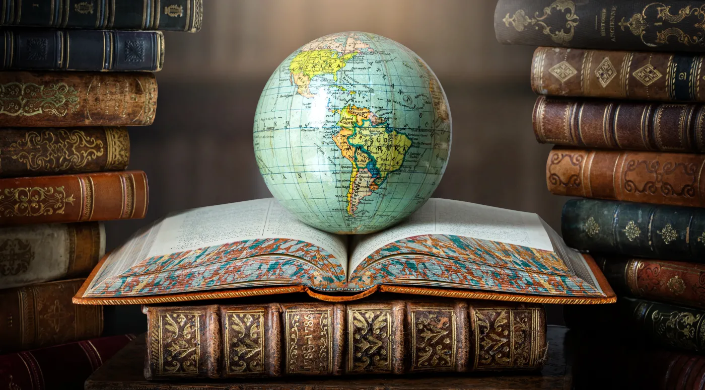 Old,Globe,Lying,On,An,Open,Book,In,A,Library.