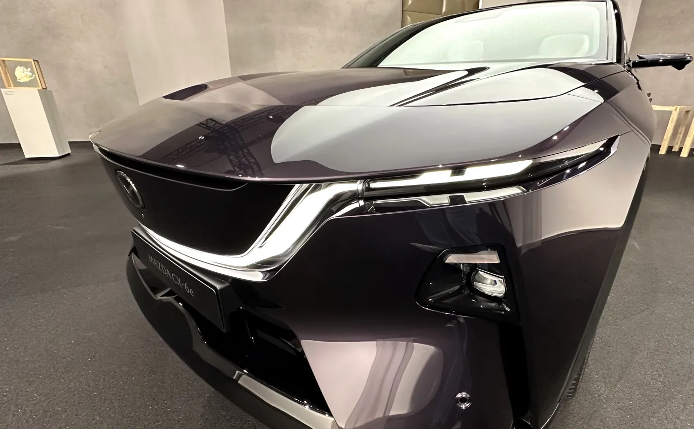 Przód nowej Mazdy CX-6e w kolorze fioletowym, z bliska widoczne nowoczesne reflektory LED i podświetlany grill, premiera Poznań Motor Show