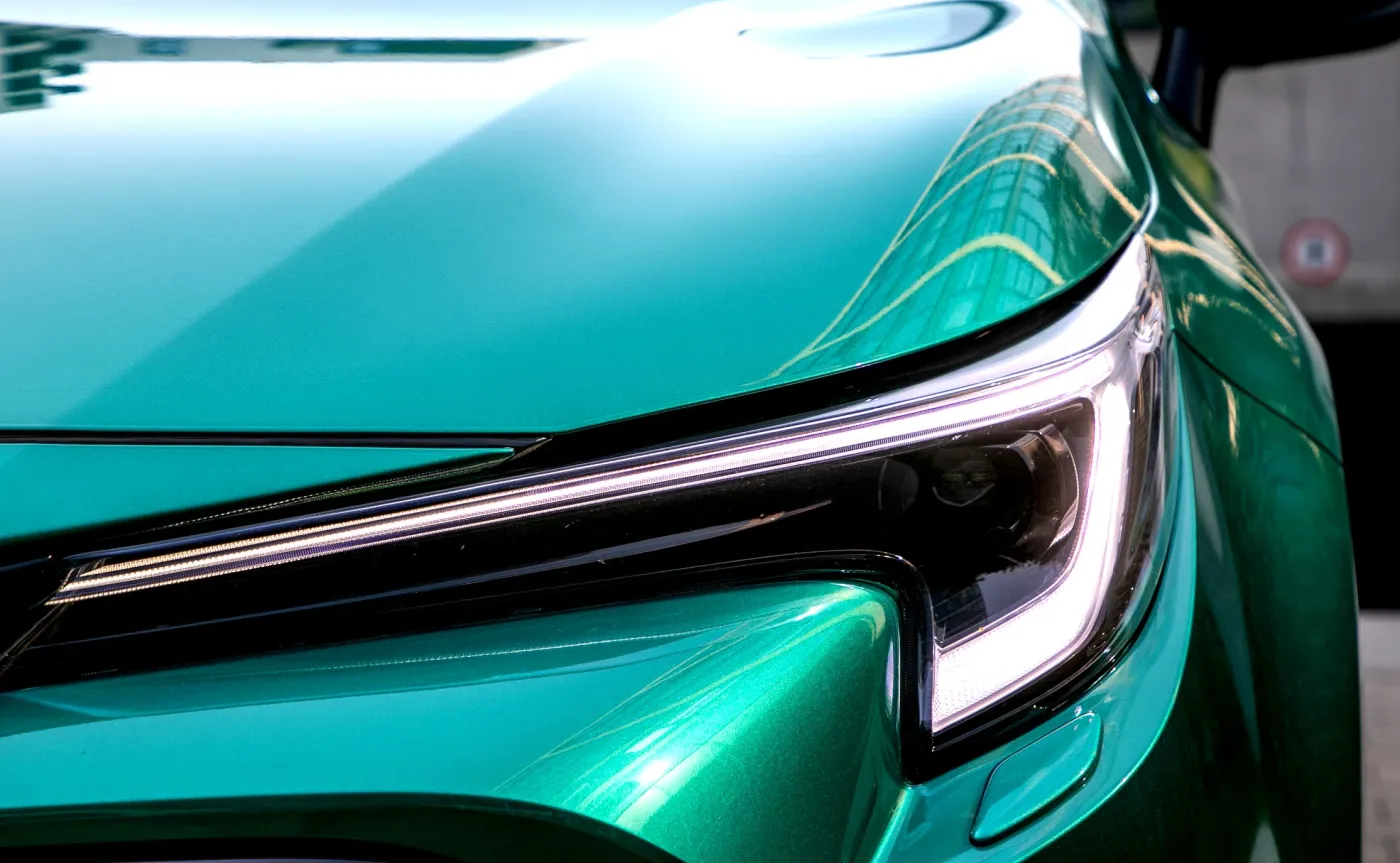 Zbliżenie na przedni reflektor LED i nasycony zielony lakier nowej Toyoty Corolli z rocznika 2026