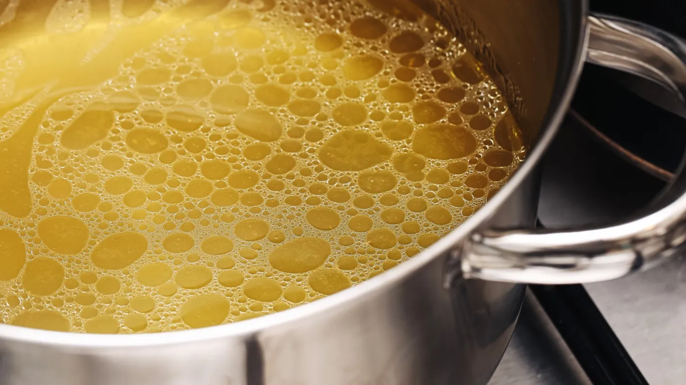 Homemade,Chicken,Broth,Simmering,In,Stainless,Steel,Pot,On,Stove.