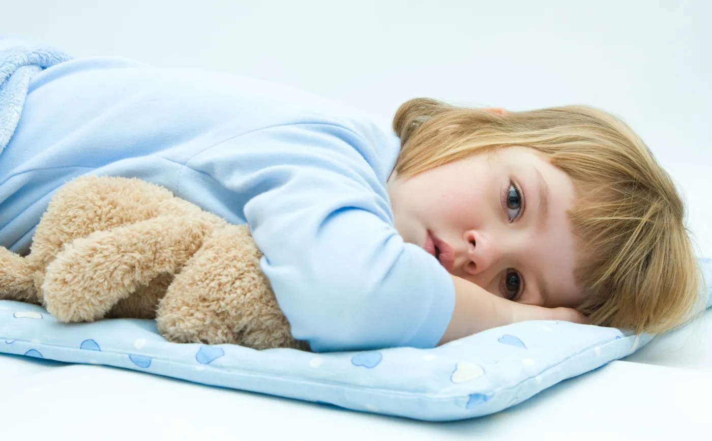 Dziecko leży z maskotką