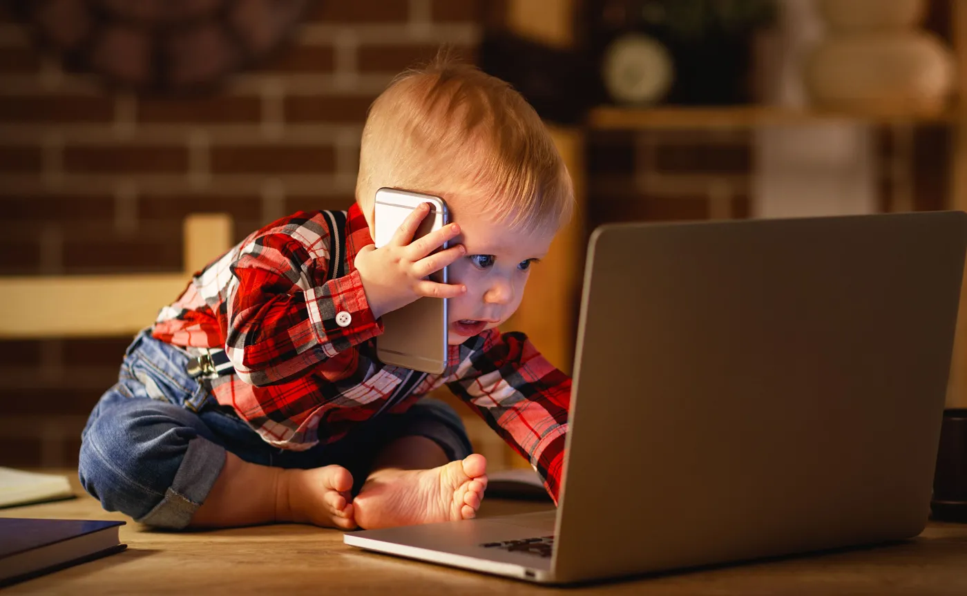 Dziecko bawi się telefonem i komputerem