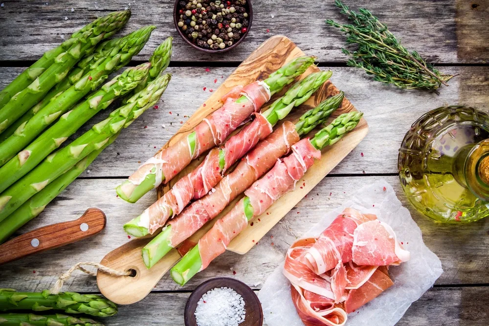 Fresh,Organic,Asparagus,Wrapped,In,Parma,Ham,On,A,Cutting