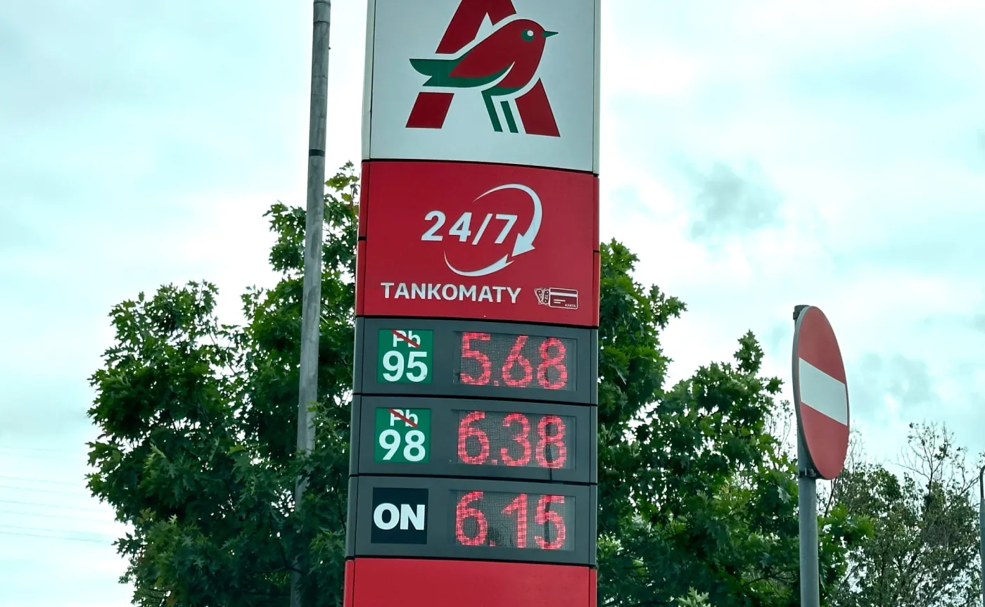 Pylon stacji benzynowej Auchan pokazujący ceny paliw: benzyna 95 za 5,68 zł, 98 za 6,38 zł oraz ON za 6,15 zł na tle drzew i nieba