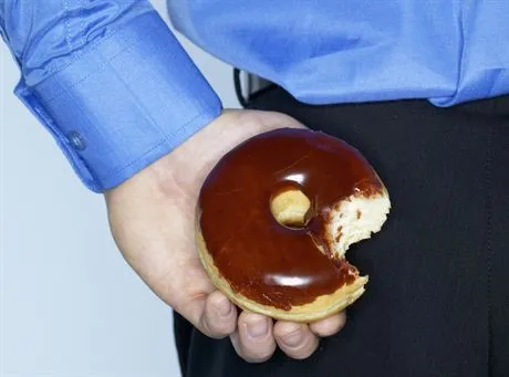 Young man hiding doughnut --- Image by  Nation WongzefaCorbis