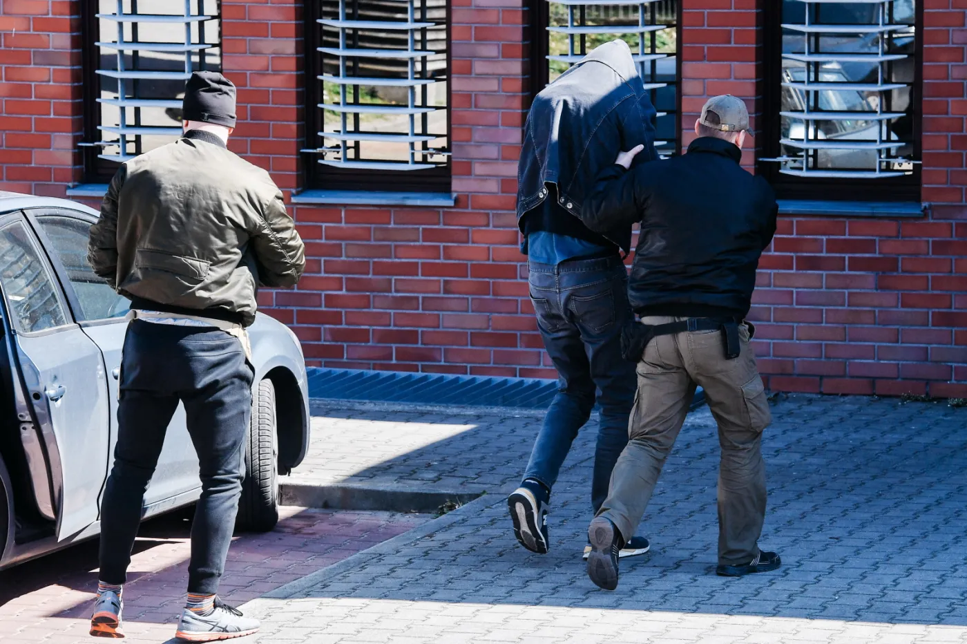 Były piłkarz Jarosław B. (C) doprowadzany do Komendy Miejskiej Policji w Sopocie