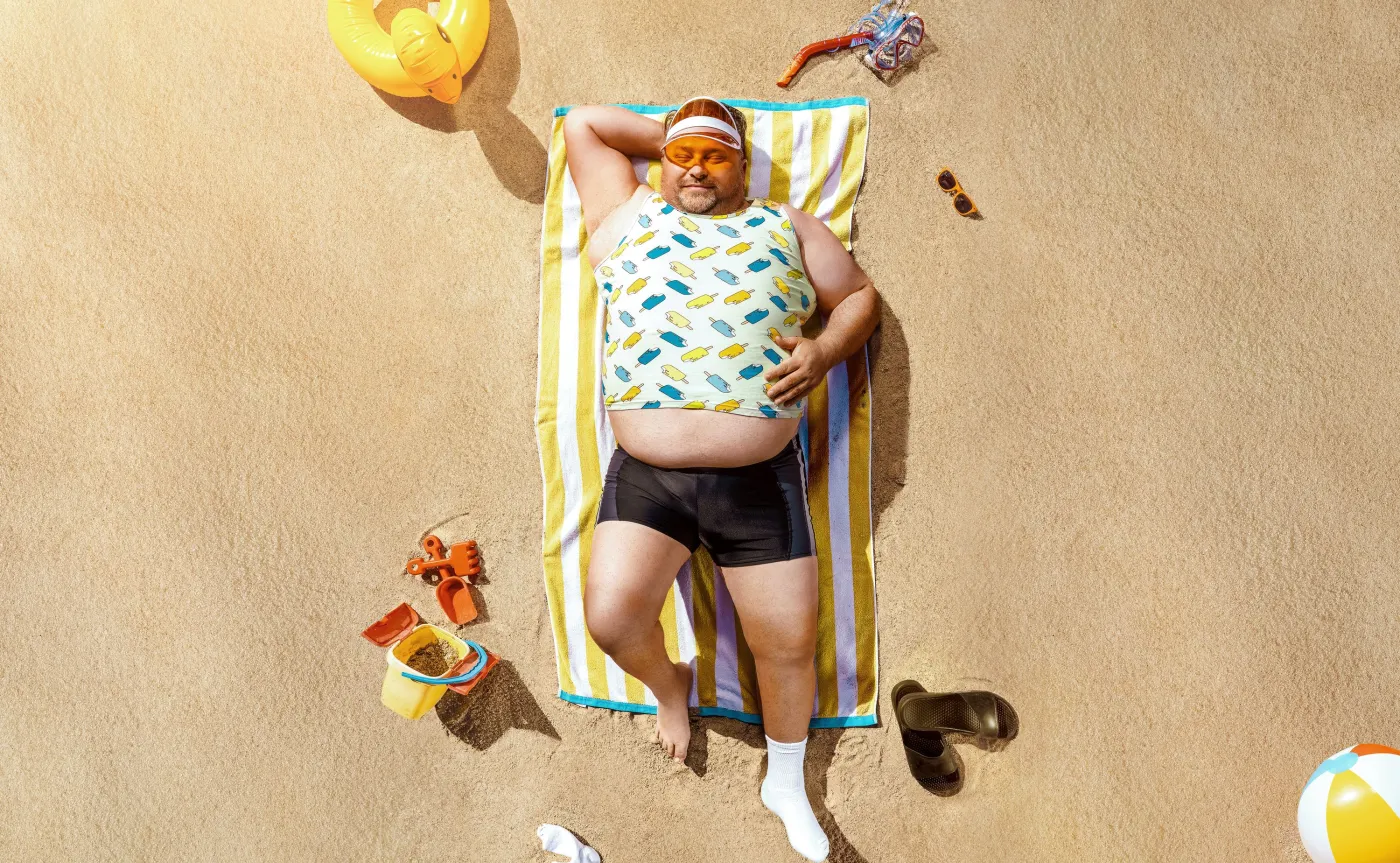 Lenistwo. Wakacje, plaża, otyły mężczyzna