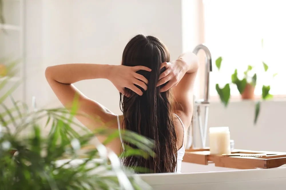 Young,Woman,Applying,Coconut,Oil,Onto,Her,Hair,In,Bathroom