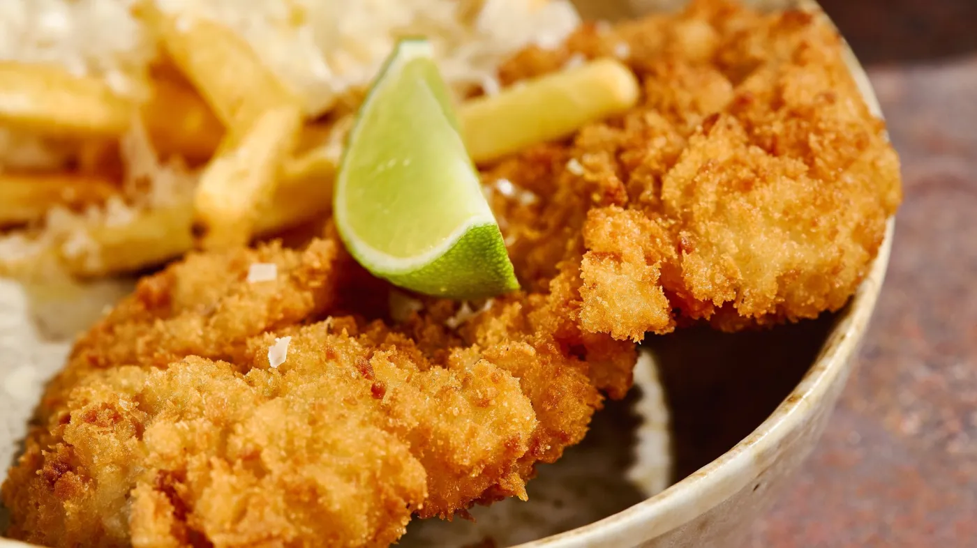 Crunchy,Breaded,Schnitzel,With,Lime,Wedge,And,Parmesan,Fries,In