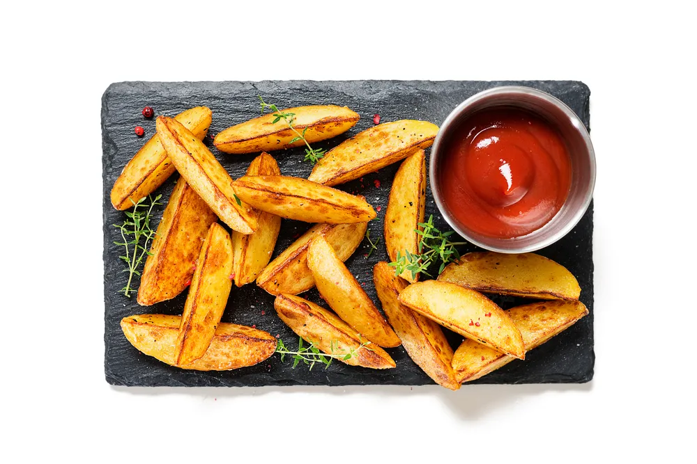 Fried,Potato,Wedges,With,Ketchup,,Herbs,On,Stone,Board,Isolated