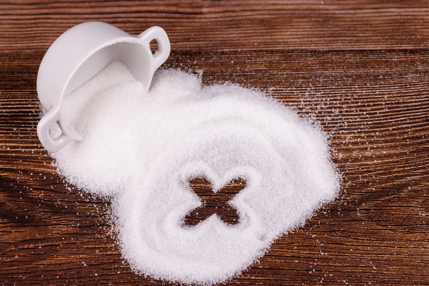 A,Ceramic,Bowl,Of,Sugar,Spilled,On,A,Wooden,Table