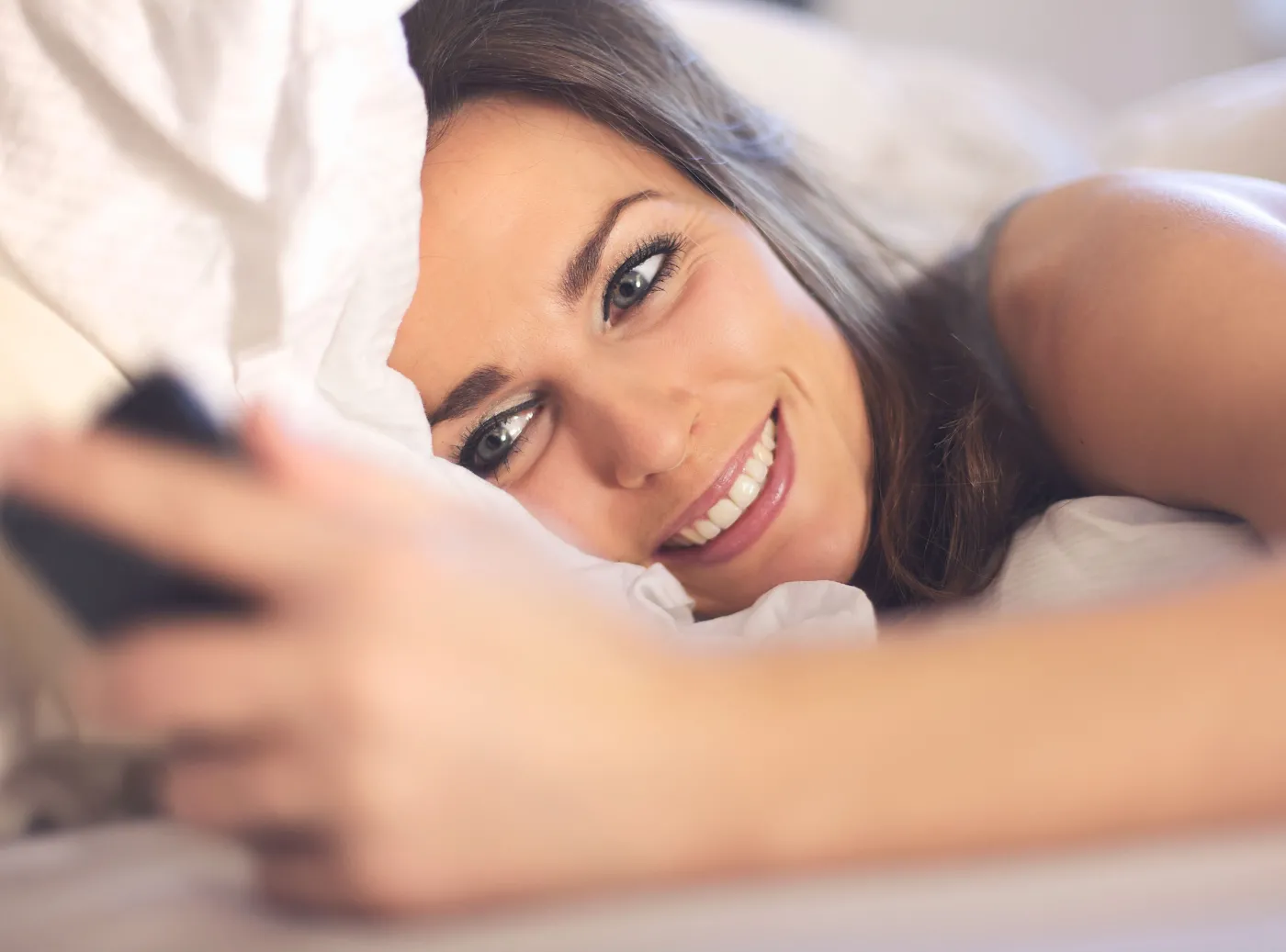 Kobieta leży w łóżku i pisze SMS-a