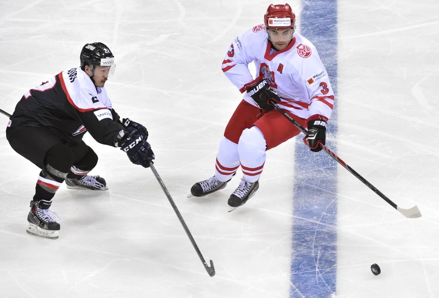 Polak Adam Bagński (P) walczy o krążek z Japończykiem Shinya Yanadori (L) podczas meczu hokejowych mistrzostw świata dywizji 1A w Krakowie