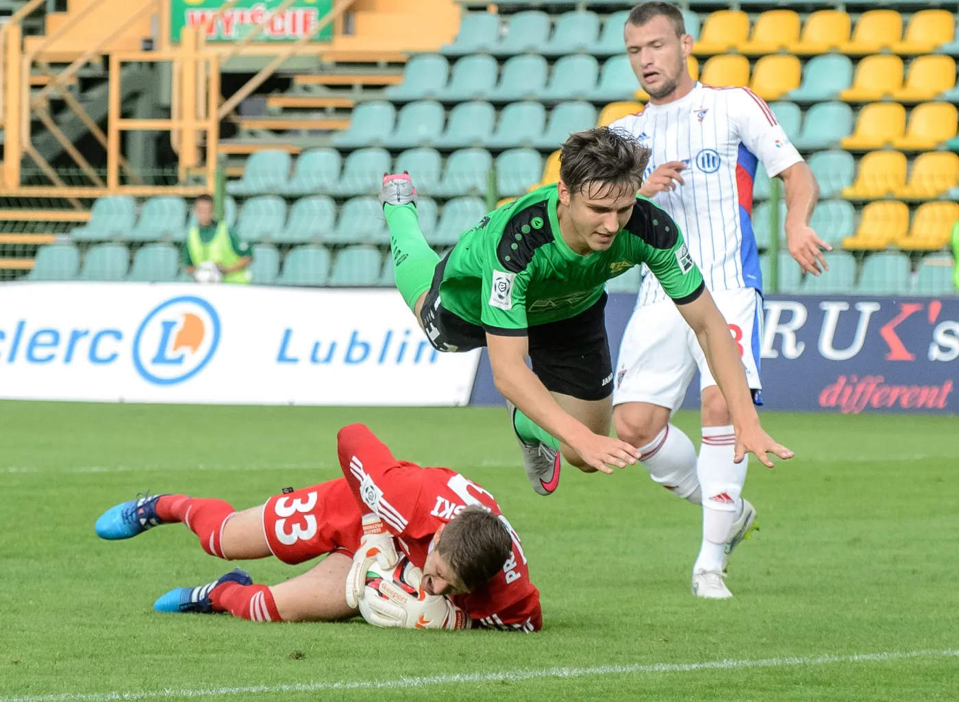 Piłkarz Górnika Łęczna Fiodor Cernych (C) przelatuje nad bramkarzem Górnika Zabrze Sebastianem Przyrowskim (L) podczas meczu polskiej Ekstraklasy