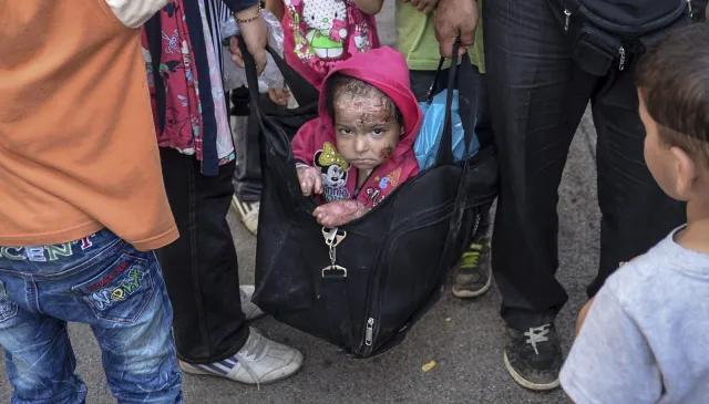Pokiereszowane dziecko imigrantów w torbie podróżnej. Fotograf: Widok trudny do wytrzymania