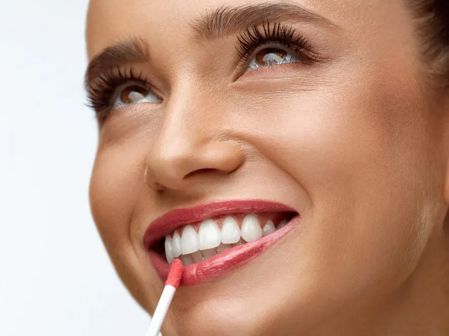 Kobieta nakłada błyszczyk na usta