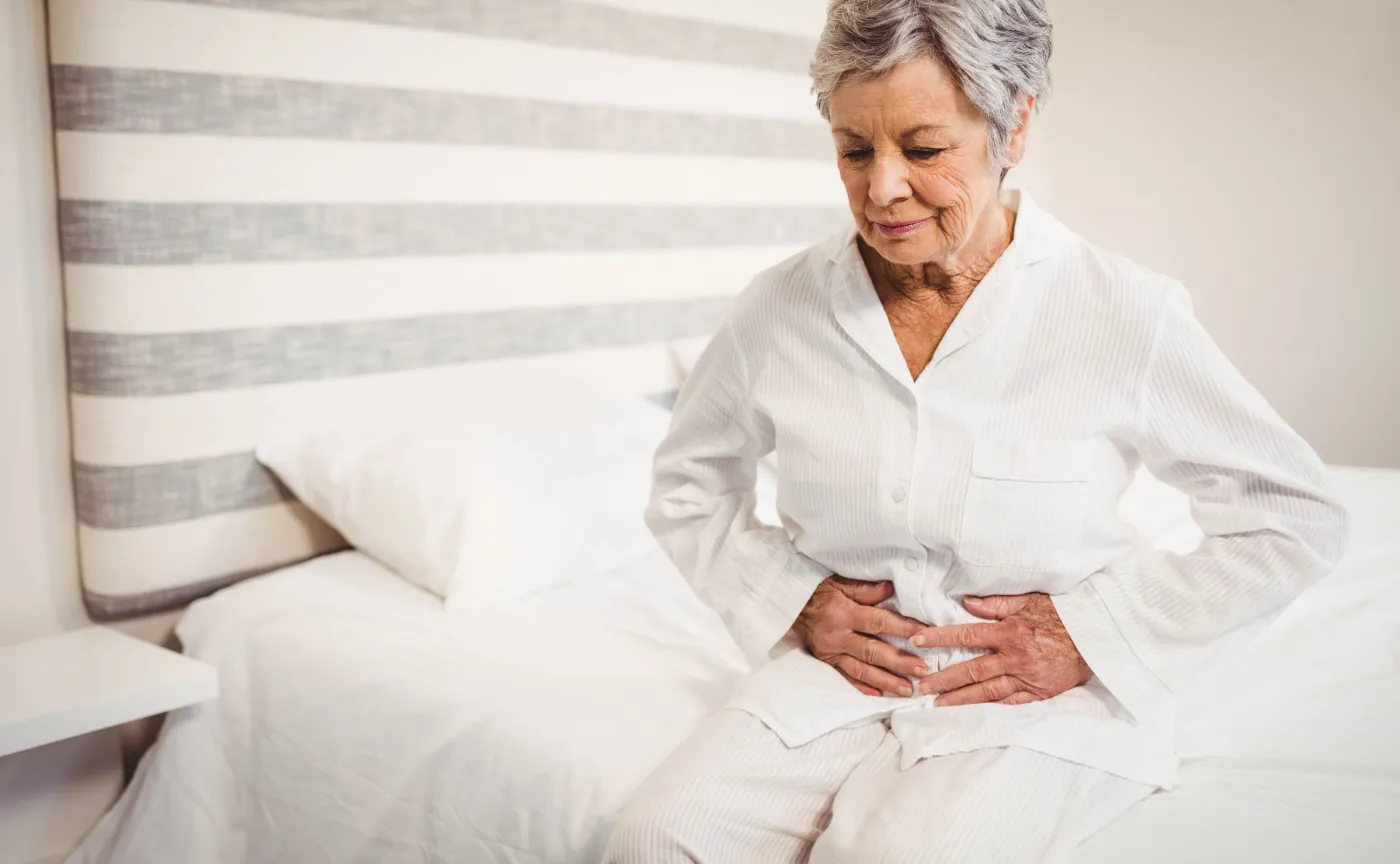 Starsza kobieta trzyma się za brzuch