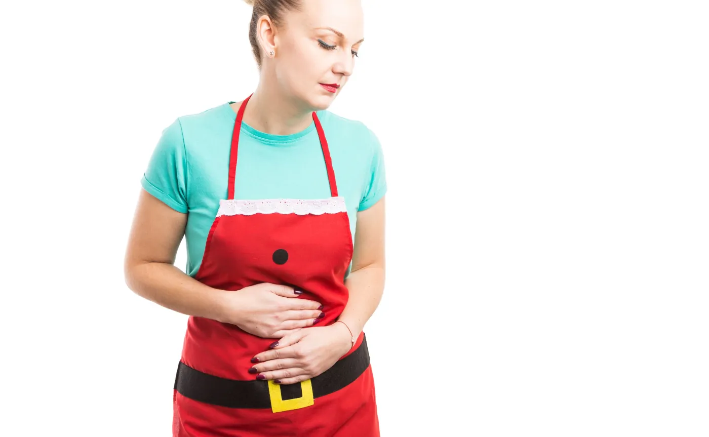 Kobieta w świątecznym stroju, trzyma się za brzuch