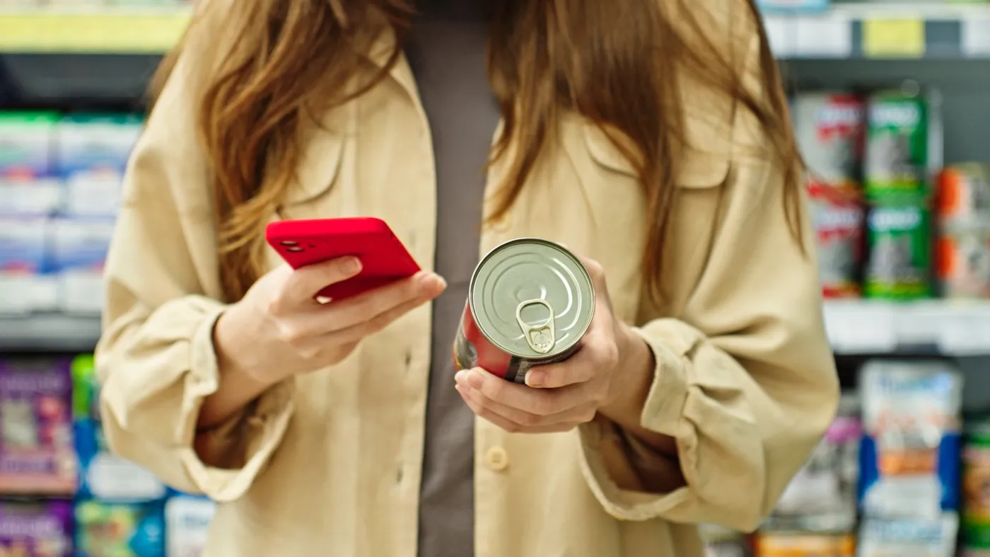 Woman,Reading,Label,Canned,Pet,Food,Checking,Information,With,Smartphone