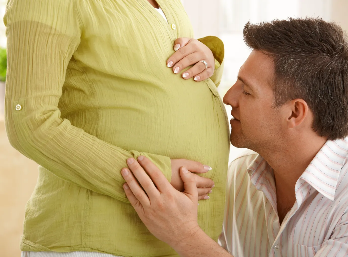 Mężczyzna całuje brzuch kobiety w ciąży