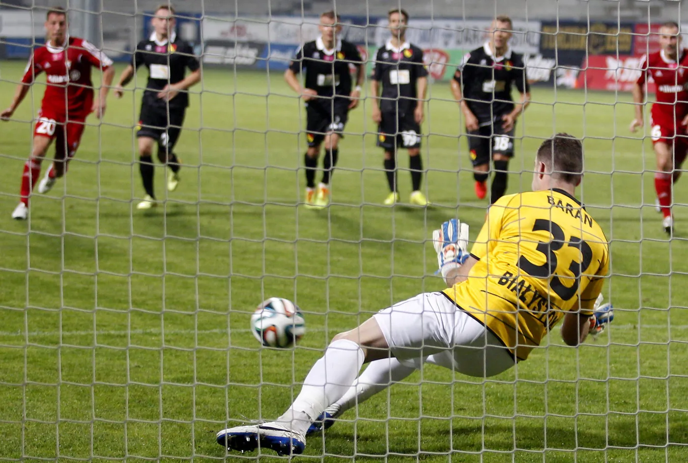 Bramkarz Jagiellonii Białystok Krzysztof Baran (#33) próbuje obronić strzał z rzutu karnego piłkarza Górnika Zabrze Roberta Jeża podczas meczu polskiej Ekstraklasy