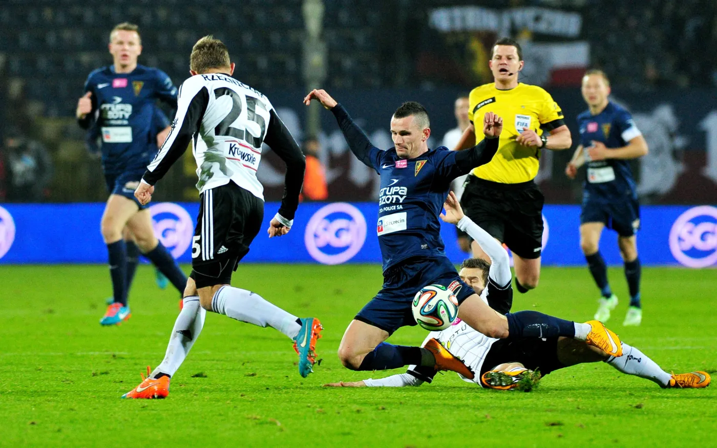 Goniący z piłką Adam Frączczak (C) z miejscowej Pogoni faulowany przez interweniującego Łukasza Brozia (P) z Legii Warszawa w meczu T-Mobile Ekstraklasy, rozegranym w Szczecinie. Z lewej - Jakub Rzeźniczak z drużyny gości. 