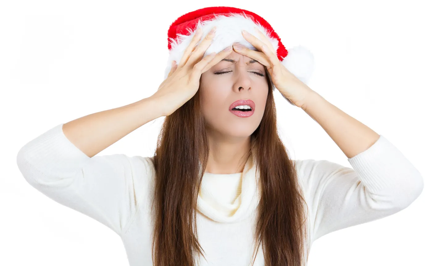 Kobieta w czapce Mikołaja trzyma się za głowę