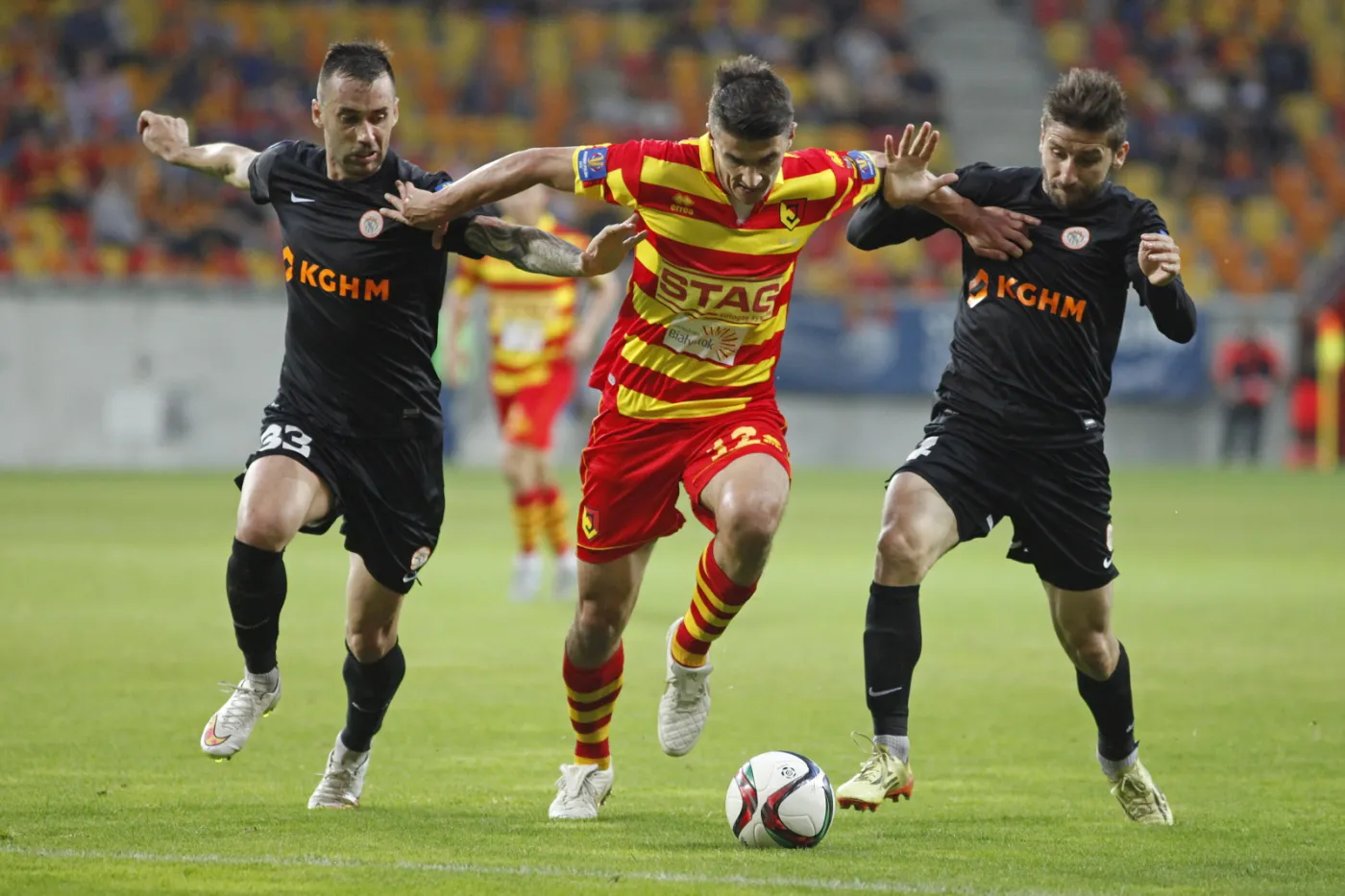 Zawodnik Jagiellonii Białystok Piotr Grzelczak (C) walczy o piłkę z Lubomirem Guldanem (L) i Aleksandarem Todorovskim (P) z KGHM Zagłębia Lubin podczas meczu 1/8 finału Pucharu Polsk