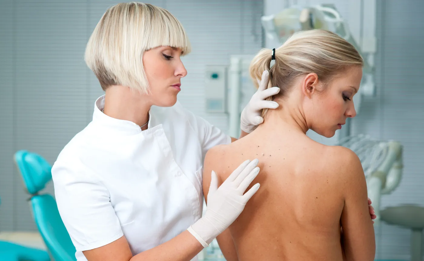 Lekarz dermatolog ogląda skórę na plecach pacjentki