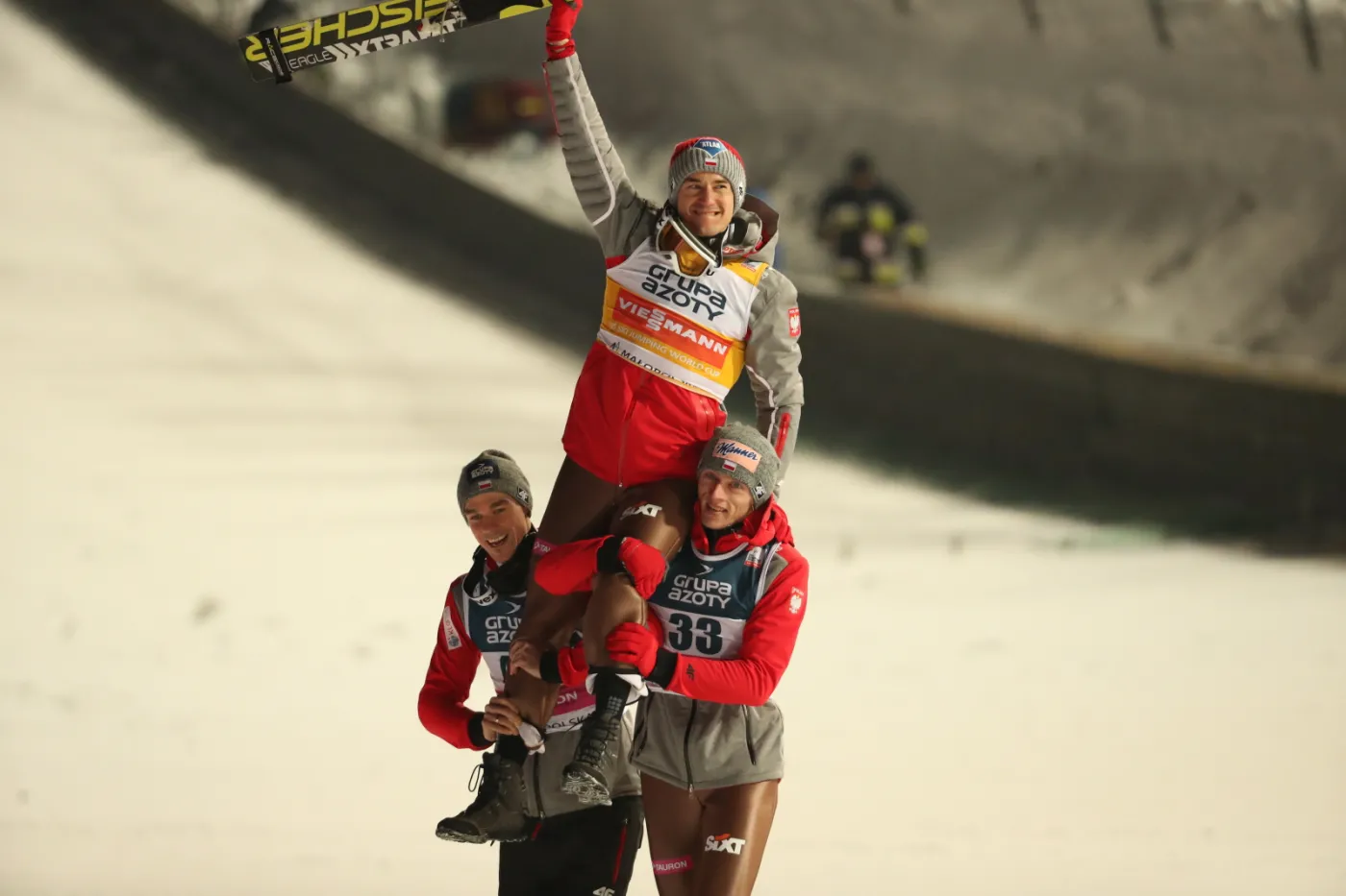 Kamil Stoch (C) noszony na rękach przez Piotra Żyłę (L) i Dawida Kubackiego (P)