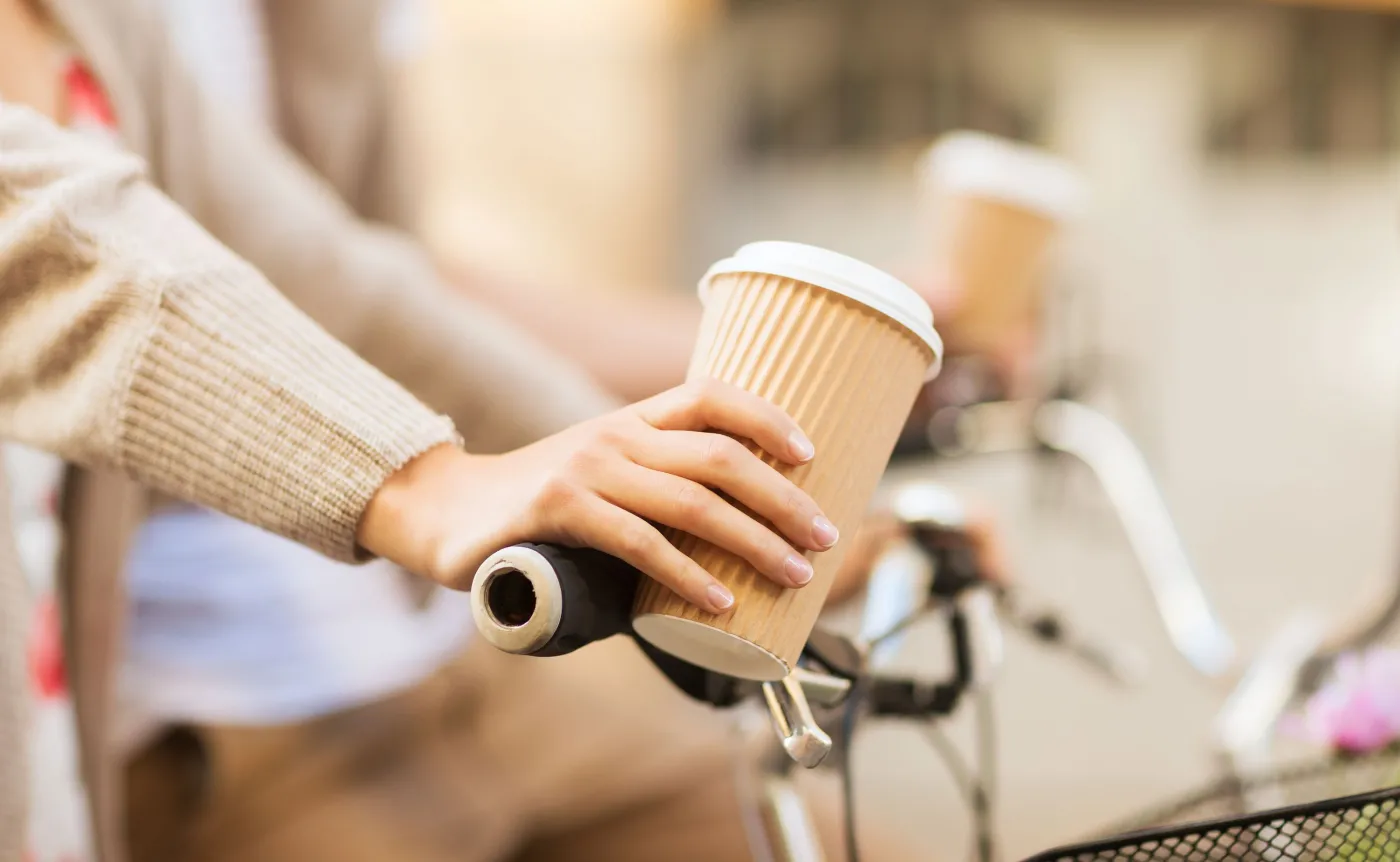 Kobieta na rowerze trzyma kubek z kawą