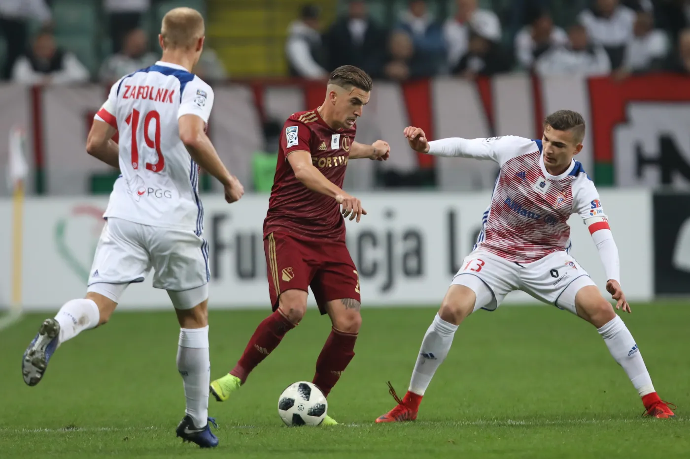 Zawodnik Legii Warszawa Carlos Lopez (Carlitos) oraz Kamil Zapolnikk (L) i Kacper Michalski (P) z Górnika Zabrze