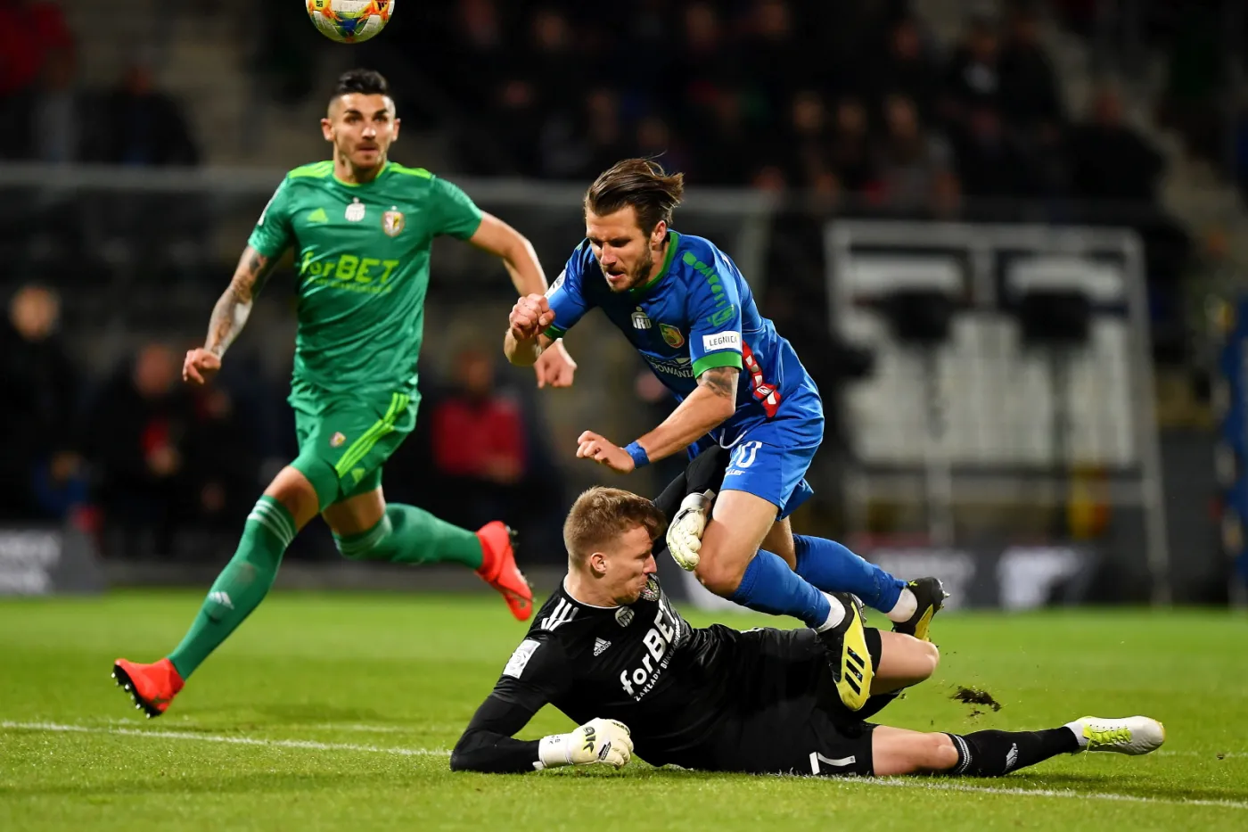 Piłkarz Śląska Wrocław Mateusz Szczepaniak (góra) i bramkarz Miedzi Legnica Jakub Słowik (dół) podczas meczu grupy spadkowej Ekstraklasy