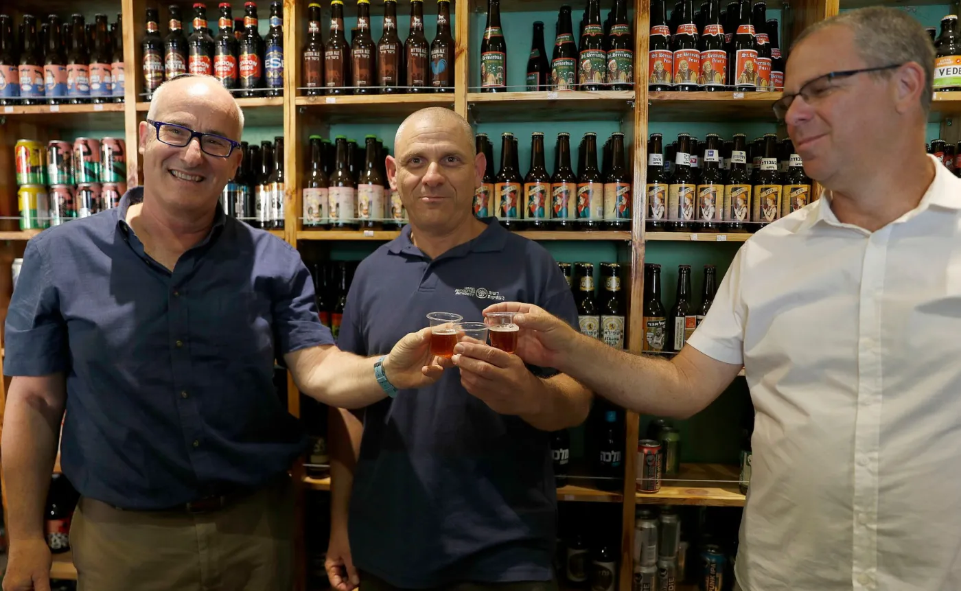 ProfesorAren Maeir (L) Dr Yitzhak Paz i profesor Yuval Gadot piją piwo zrobione ze starożytnych drożdży