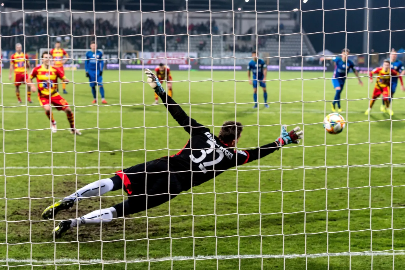 Piłkarz Jagiellonii Białystok Guilherme Sitya (L) pokonuje z rzutu karngego Antona Kanibołockiego (C) z Miedzi Leginica