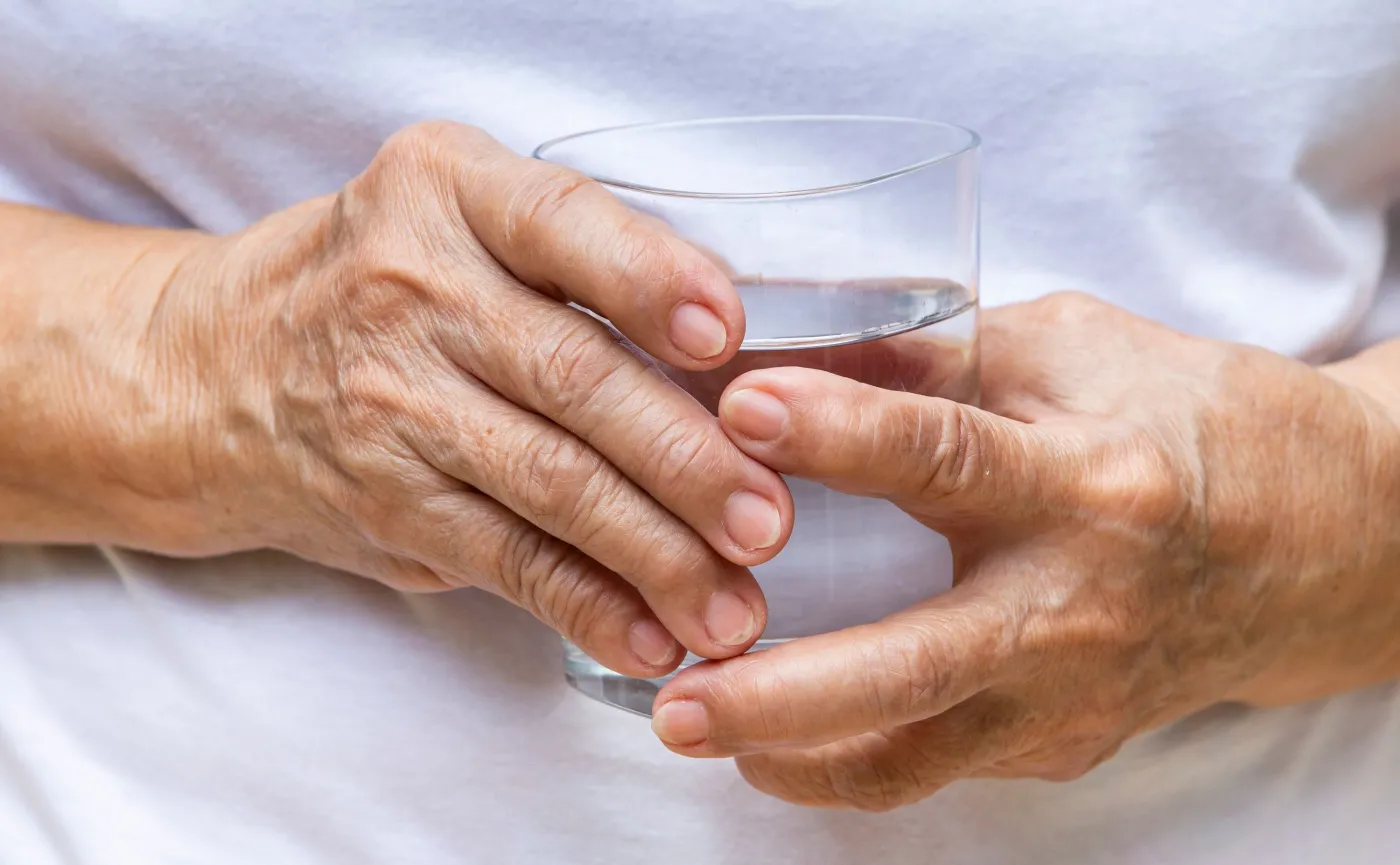 Starsza osoba trzyma szklankę z wodą