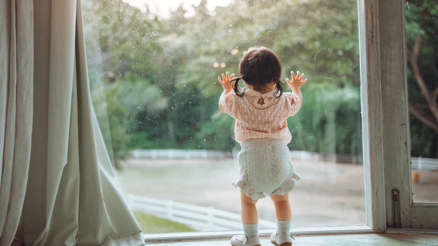Rear,View,Of,Curious,Little,Asian,Girl,Standing,And,Leaning