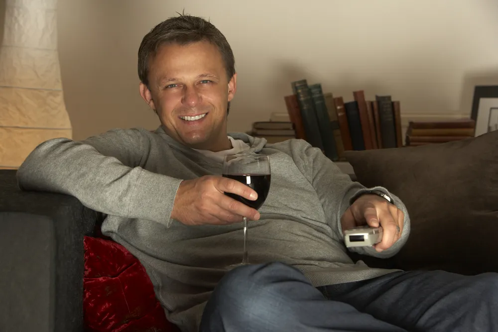 Mężczyzna z pilotem i kieliszkiem wina