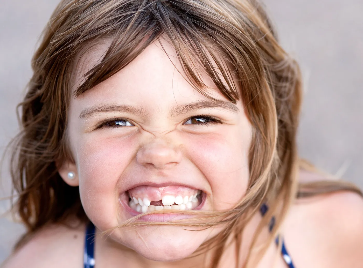 Dziewczynka uśmiecha się i pokazuje zęby