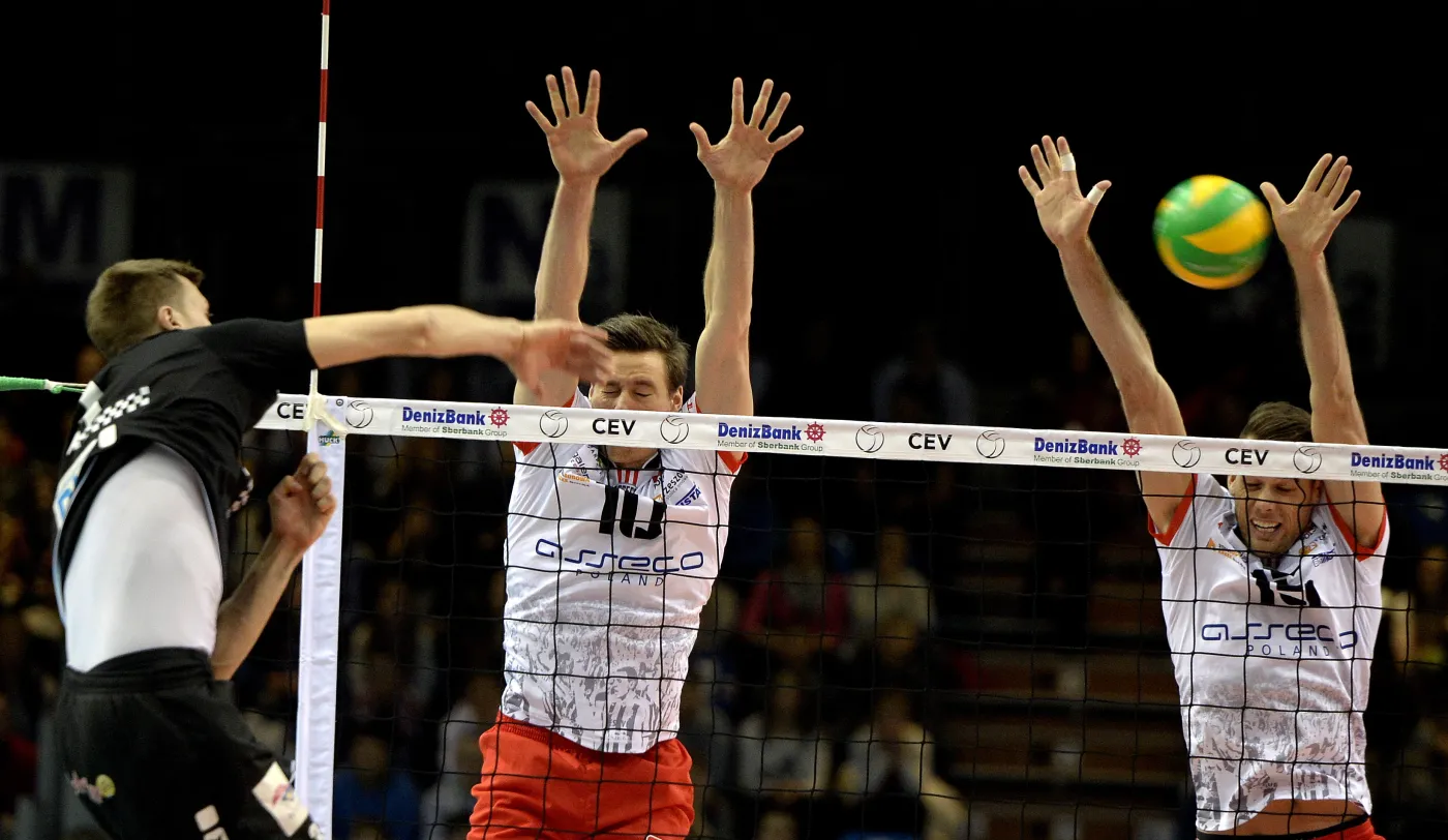 Robert Kromm (L) z Berlin Recycling Volleys atakuje po bloku Jochena Schopsa (2L) i Rusella Holmsa (P) z Asseco Resovii Rzeszów